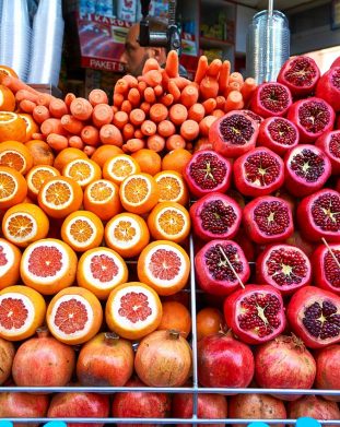 Soczyste pomarańcze, marchew i granaty na straganie na stambulskim bazarze